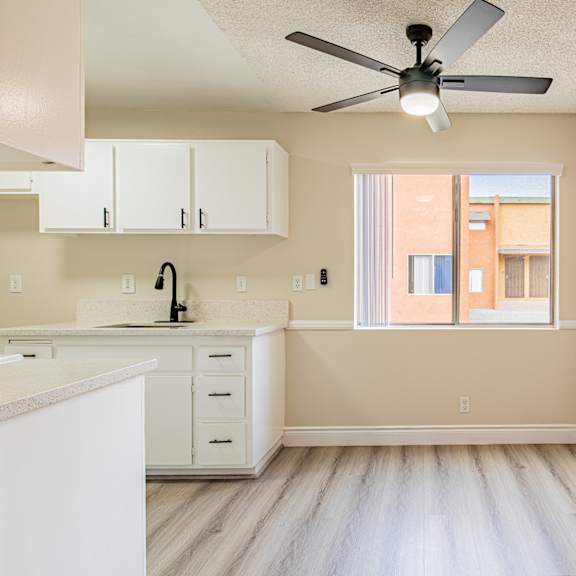 a kitchen with white cabinets and a fan on the ceiling.