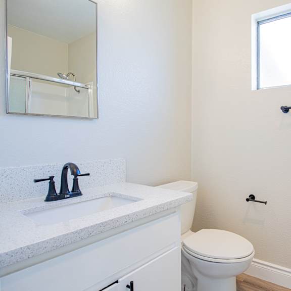 a white bathroom with a toilet, sink, and a window.