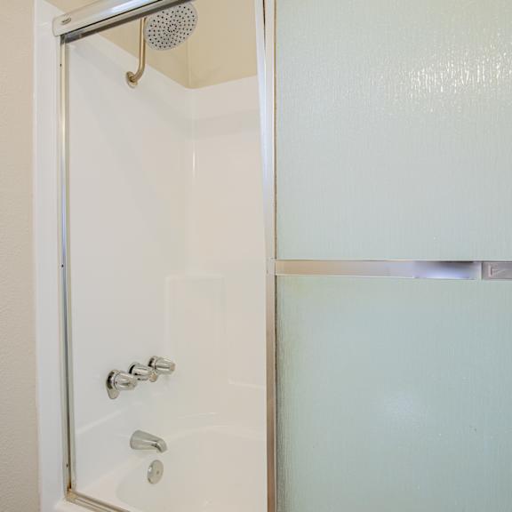 a shower with a glass door and a black handle.