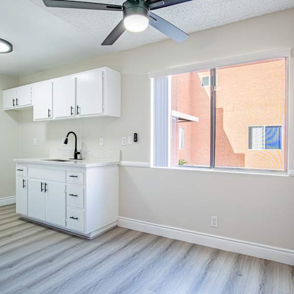 a kitchen with white cabinets and a ceiling fan.