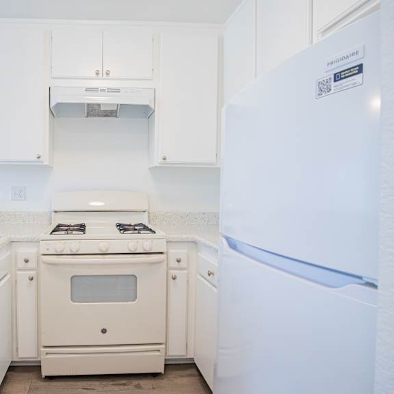 a white kitchen with a fridge on the right.