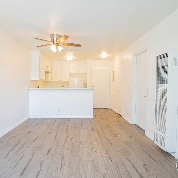 a room with a ceiling fan and wooden flooring.