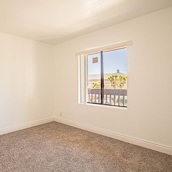 a room with a carpeted floor and a window showing a balcony.