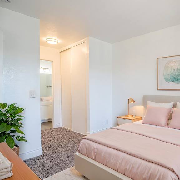 a bedroom with a pink bed and a painting on the wall.