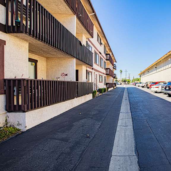 a long, narrow road with cars parked on the side.
