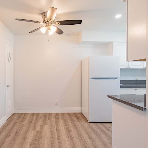 a kitchen with a white fridge and a ceiling fan.