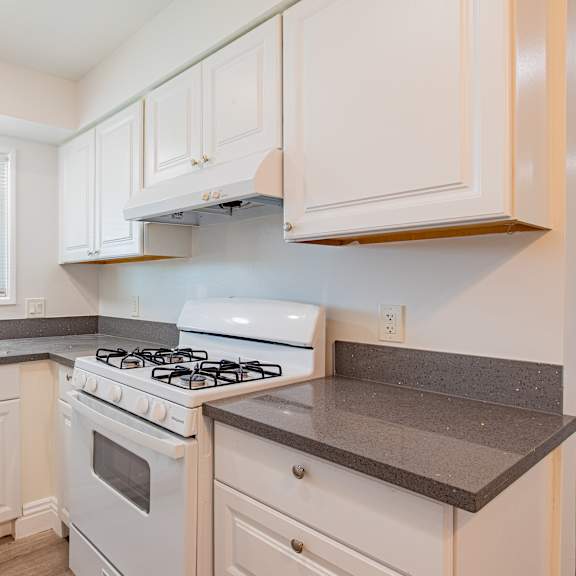 a white kitchen with a stove and sink.