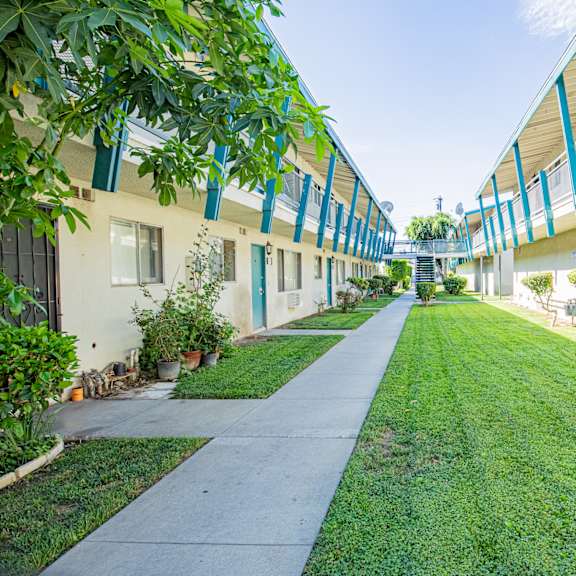 a long, narrow walkway between two buildings with greenery on the sides.