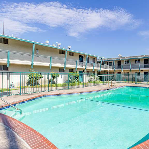 a swimming pool in front of a building with a clear blue sky.