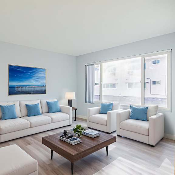 a living room with a large painting on the wall and two white couches.