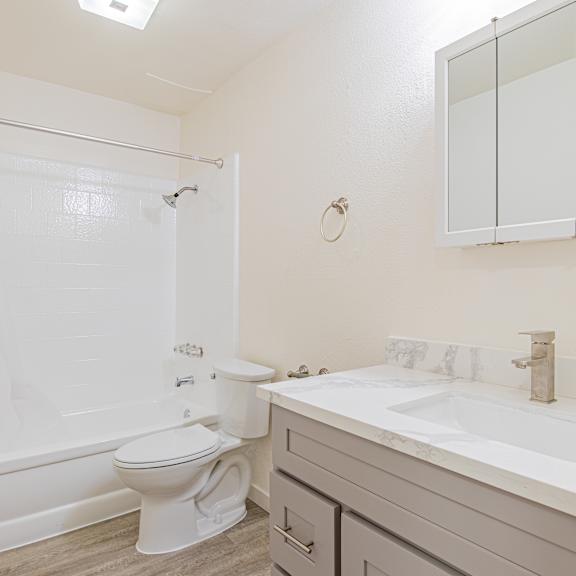 a white bathroom with a toilet, sink, and shower.