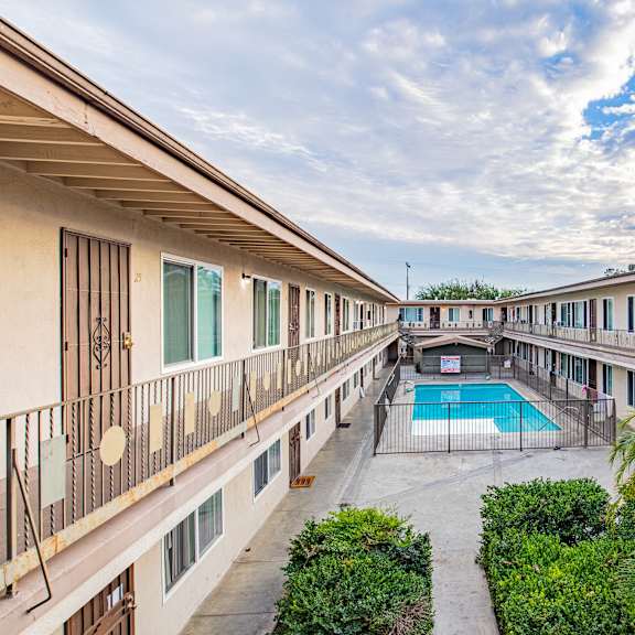 a balcony overlooks a pool surrounded by greenery.