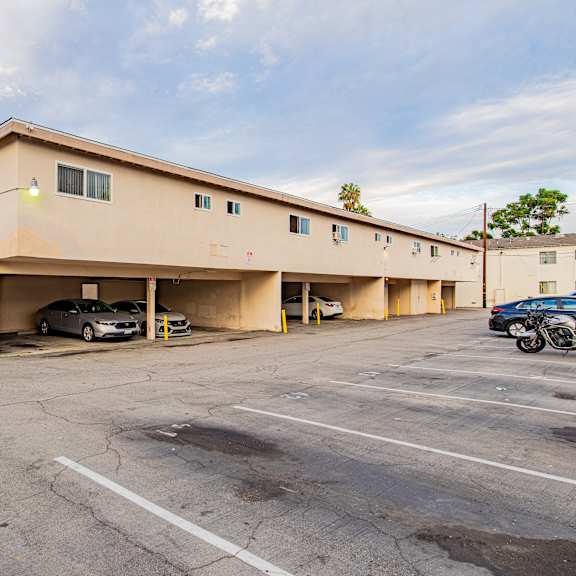 a parking lot with a building in the background and cars parked in the lot.