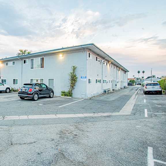 a parking lot with cars and a white building in the background.