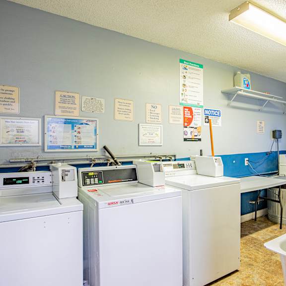 a laundromat with washers and dryers and signs on the wall.