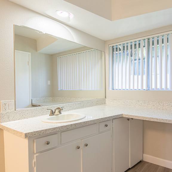 a bathroom with a sink, mirror, and cabinets.