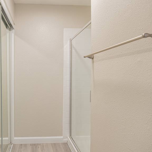 a white bathroom with a glass shower door and a white towel rack.