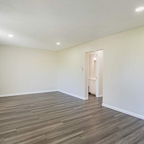 a room with a wooden floor and a white ceiling with a heater on the left side.