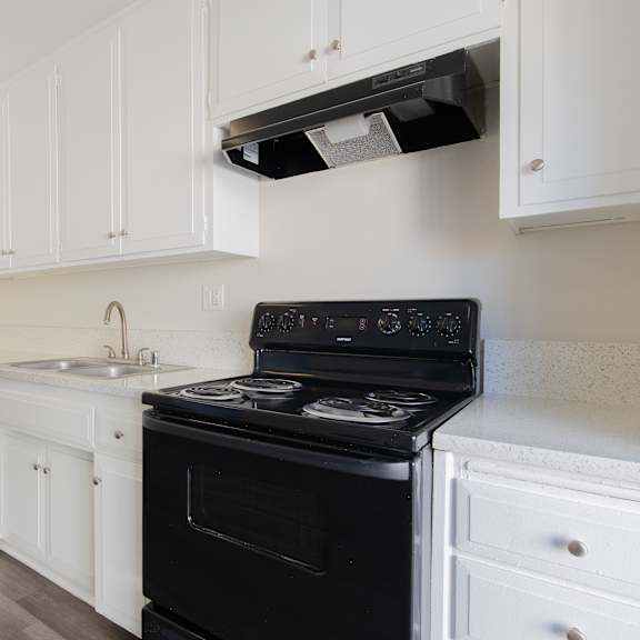 a black stove in a kitchen with white cabinets.