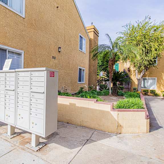 a mailbox is on the sidewalk in front of a tan building.