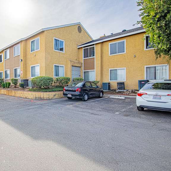 a parking lot in front of a yellow apartment building.