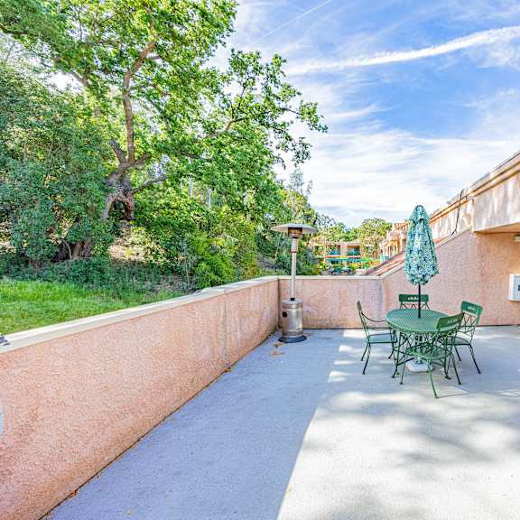 a patio with a table and chairs is surrounded by trees.