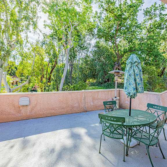 a patio with a table and chairs and a green umbrella.