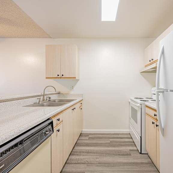 a kitchen with a white refrigerator, sink, and cabinets.