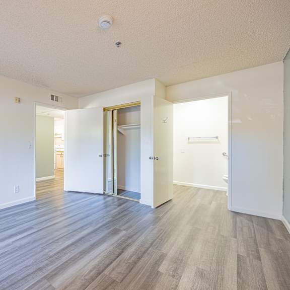 a room with a white ceiling and wooden flooring with a door on the right.