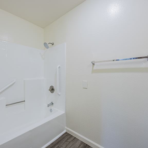 a white bathroom with a walk in shower and a towel bar.