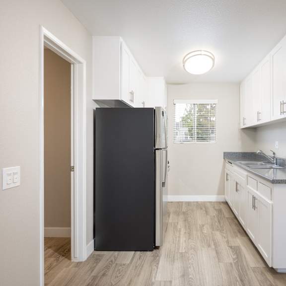 a kitchen with a black refrigerator and white cabinets.