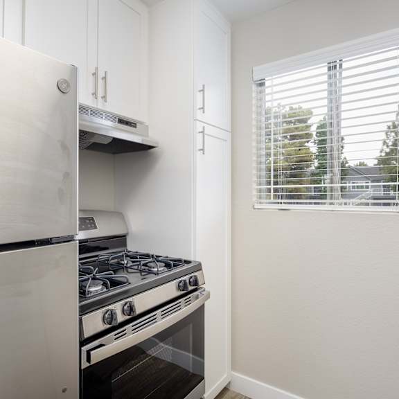 a white fridge and stove in a kitchen with a window.