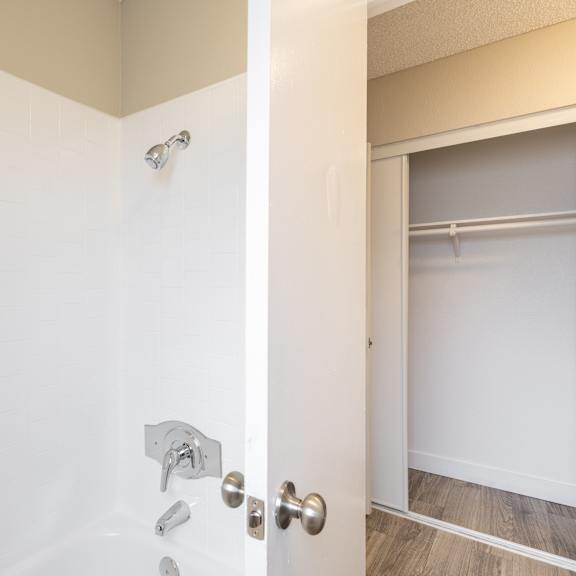 a white door with a silver handle and a silver shower head.