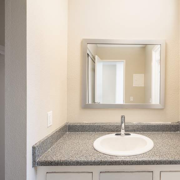 a bathroom sink with a granite counter top and a mirror above it.