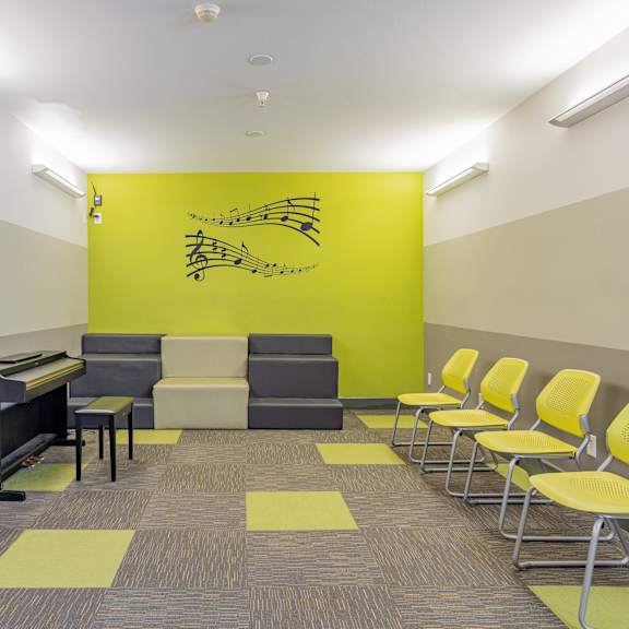 a waiting room with yellow chairs and a piano at international village ucr student housing, riverside california