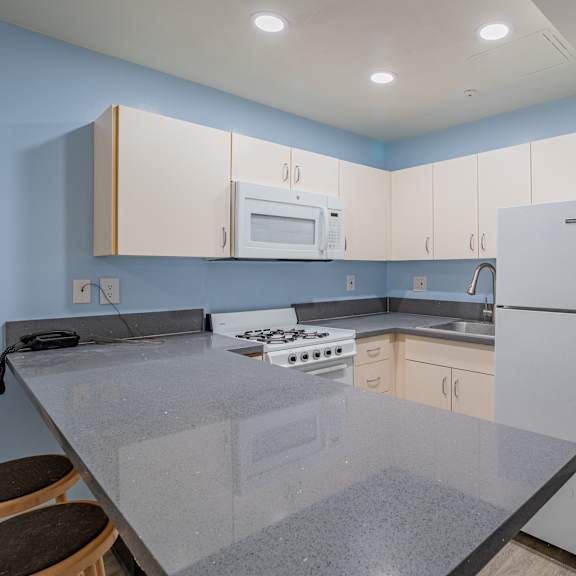 a kitchen with white cabinets and a counter top and a refrigerator at international village ucr student housing, riverside, ca 92507
