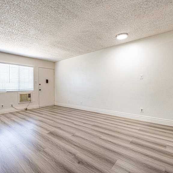 a room with wooden flooring and a window with blinds.