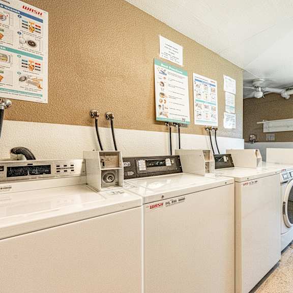 a laundromat with washers and dryers and signs on the wall.