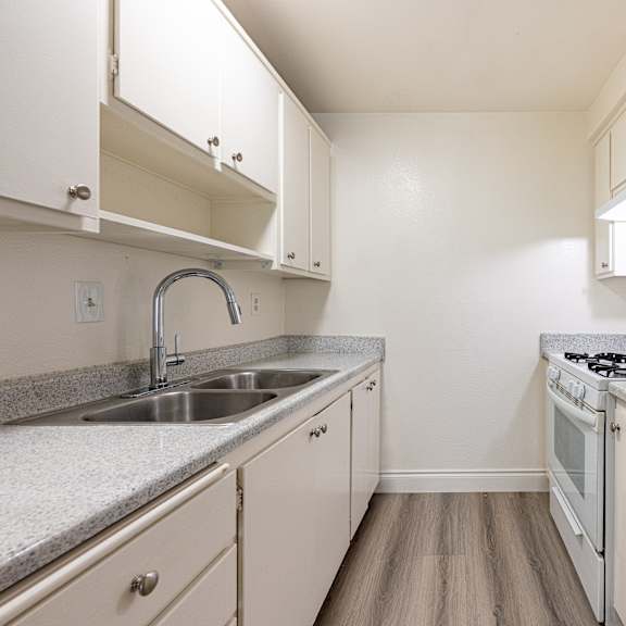 a small kitchen with a sink, stove, and cabinets.