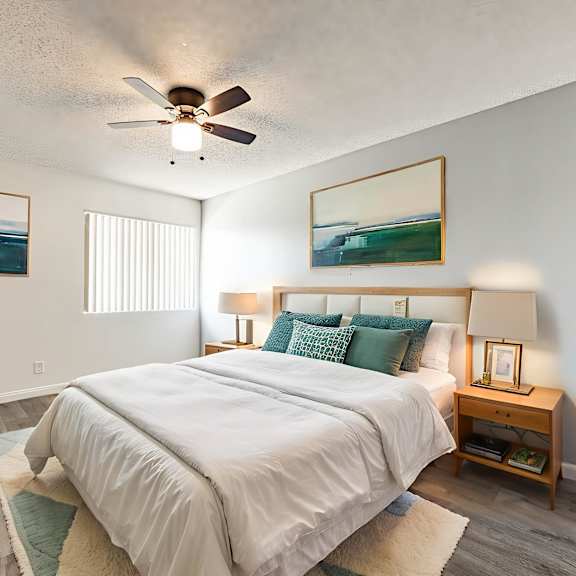 a bedroom with a large bed, a ceiling fan, and two pictures on the wall.