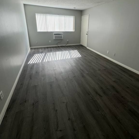a room with wooden flooring and a window with blinds.