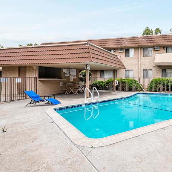 a swimming pool in front of a building with a red tiled roof.