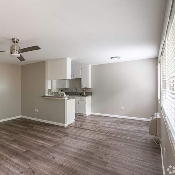a spacious room with a kitchenette and a ceiling fan.