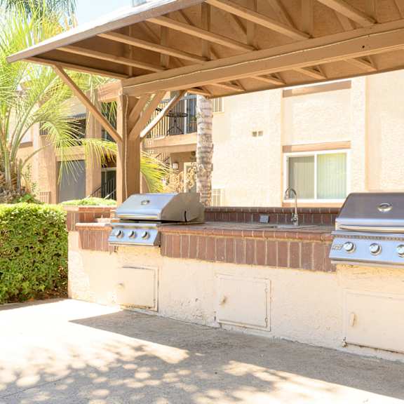 an outdoor kitchen with two grills and a sink at oak terrace senior apts, hemet, ca