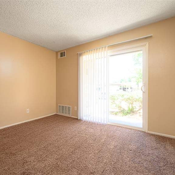 a bedroom with a sliding glass door and a carpeted floor at oak terrace senior apts, california, 92543