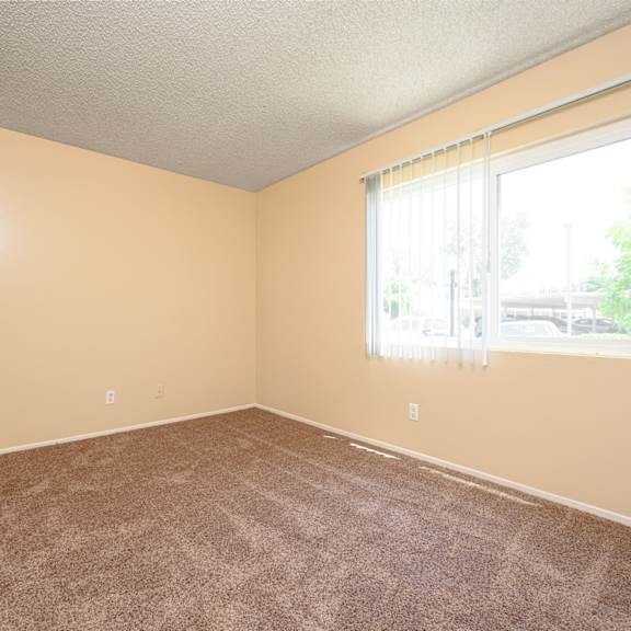 a bedroom with a large window and a carpeted floor at oak terrace senior apts, california