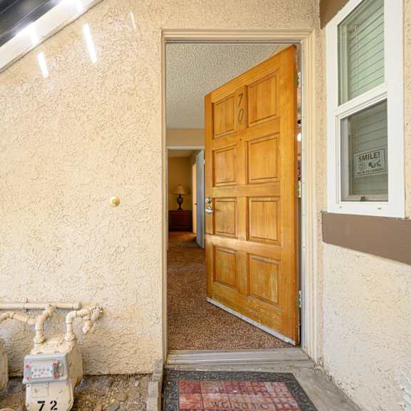 an open door leading to a hallway with a wooden door and white boxes in front of it at oak terrace senior apts, hemet california