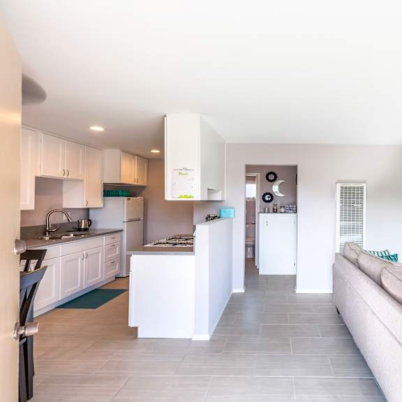 a modern kitchen with a large island and a living room with a couch.