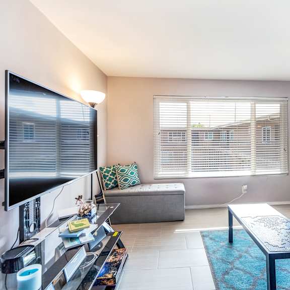 a living room with a grey couch, a blue coffee table, and a flat screen tv.