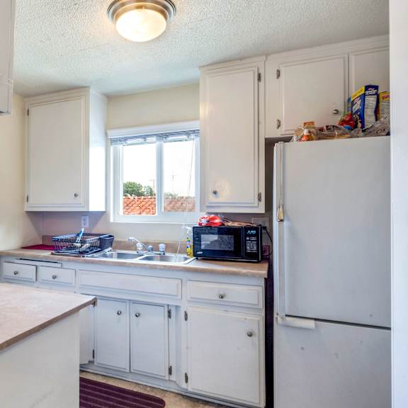 a kitchen with white cabinets and a white refrigerator.